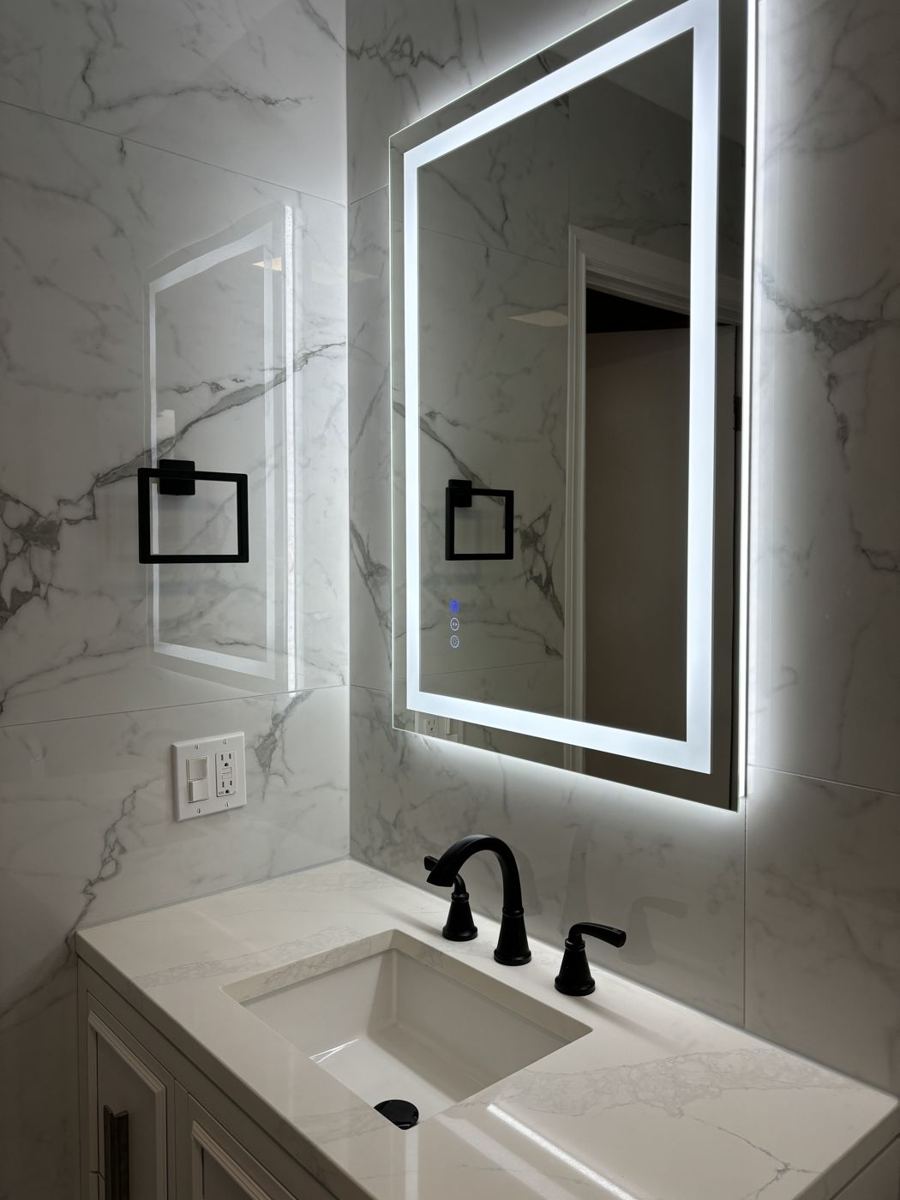 Bathroom with marble-look tile and a lit mirror