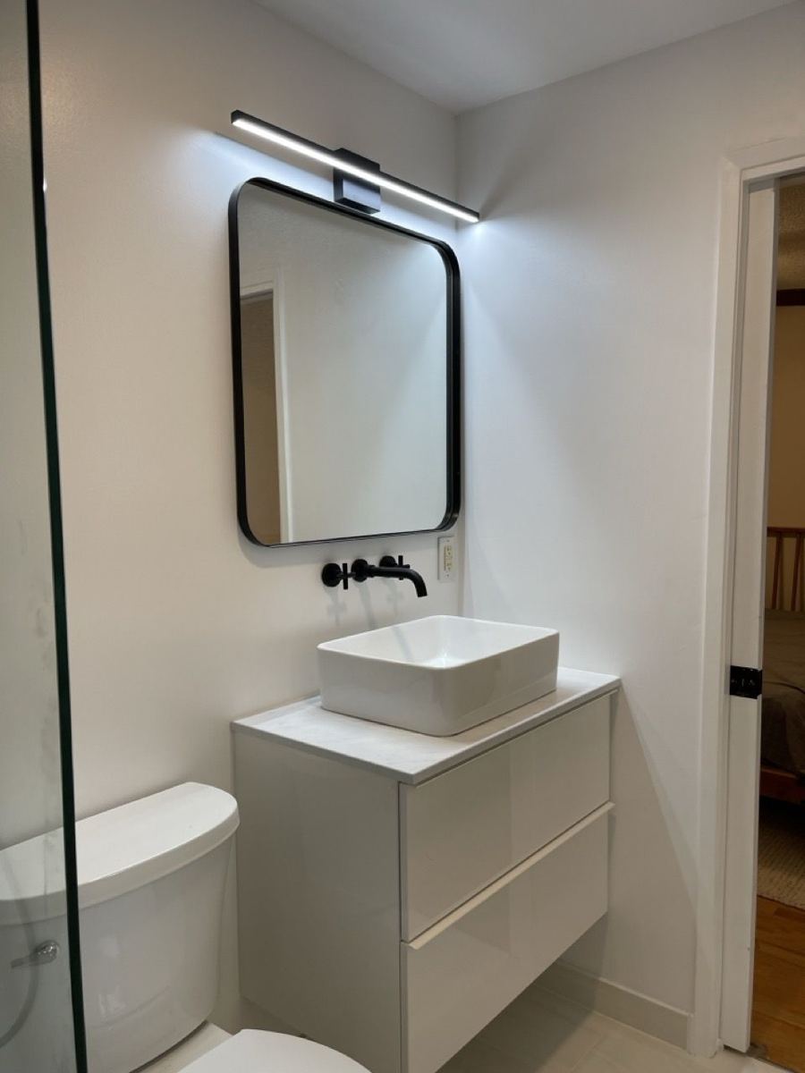 Floating vanity with a vessel sink and black mirror