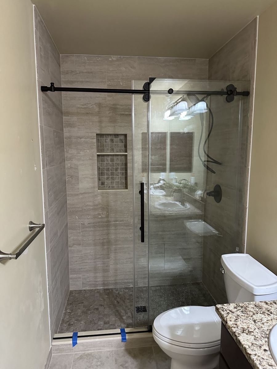 Walk-in shower with a sliding glass door and niche