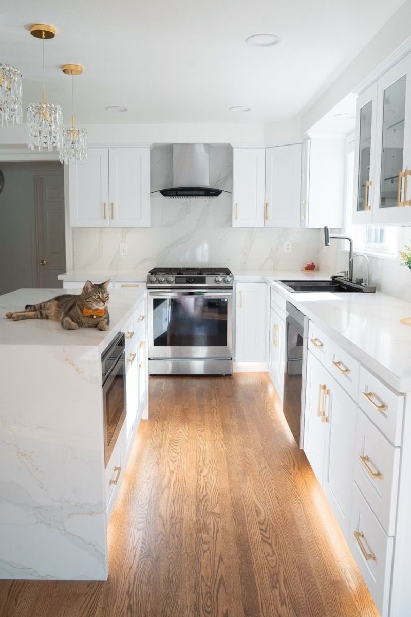 Galley kitchen with white cabinets and wood floors