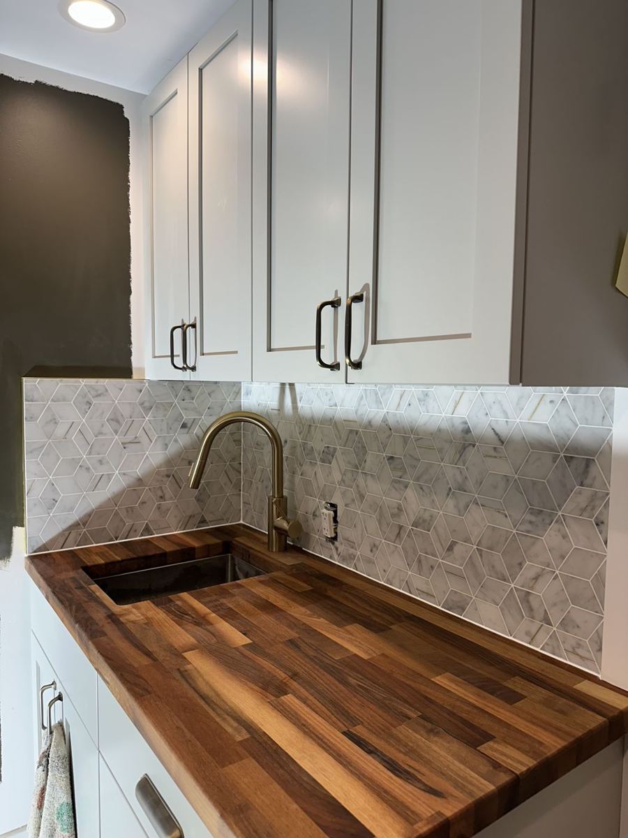 Butcher block counter with a gold faucet and tile backsplash